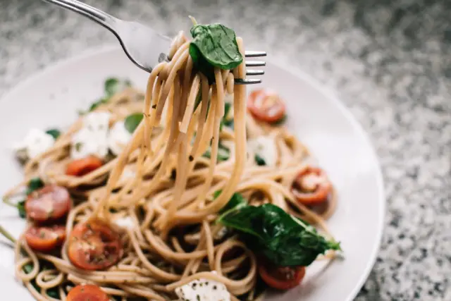 Spaghetti with cherry tomatoes and basil twirled on a fork